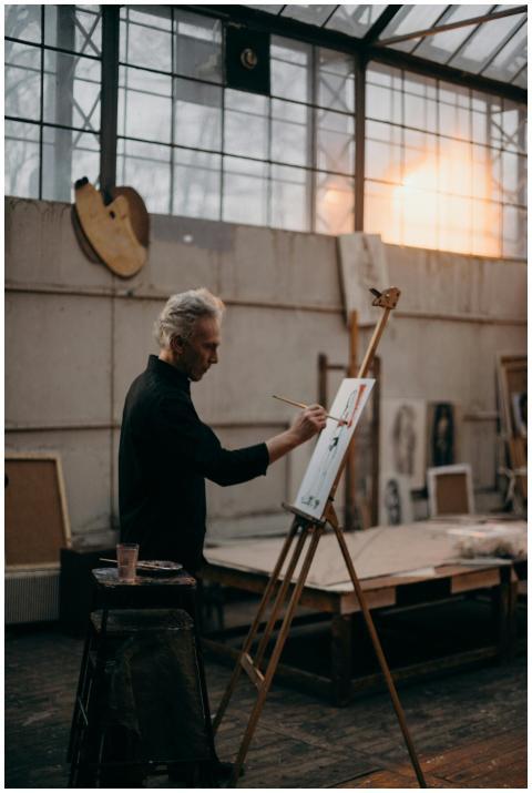 Elderly artist painting on canvas with concentrati