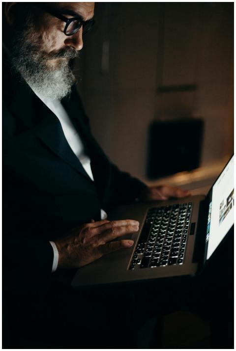 A bearded man in a suit working on a laptop, captu