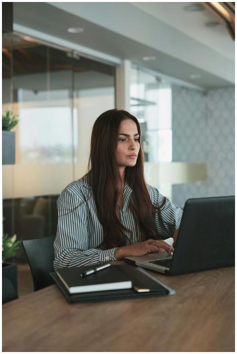 Focused businesswoman typing on laptop in a stylis