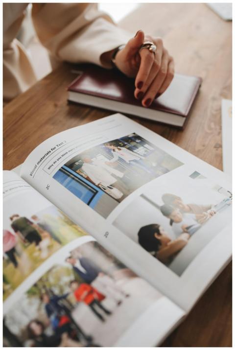 Close-up of an open book on a table with a hand re