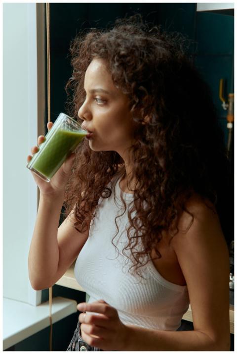 Young woman with curly hair drinking a nutritious