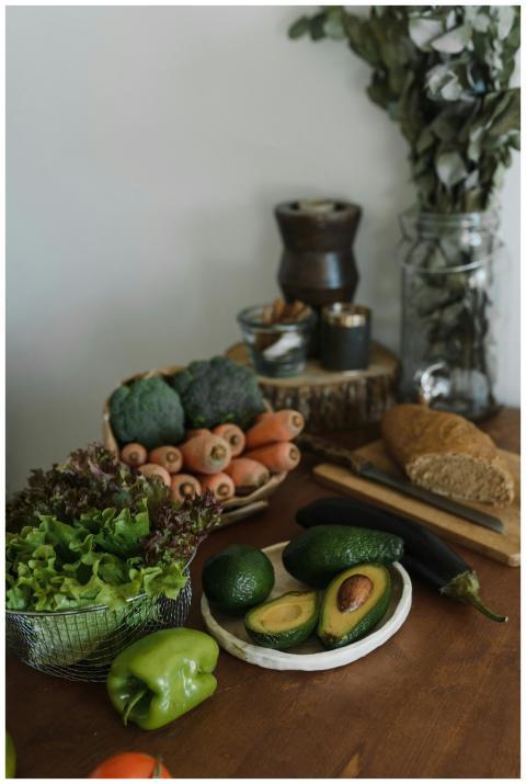 A rustic still life of fresh vegetables, avocados,