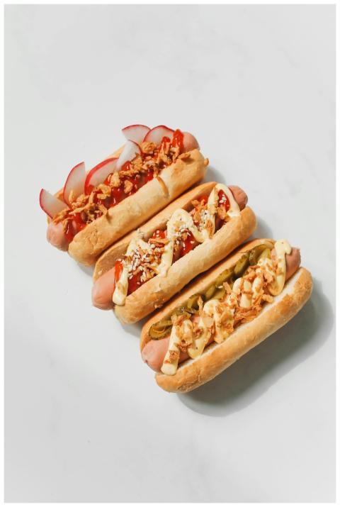 Three gourmet hot dogs with creative toppings on a