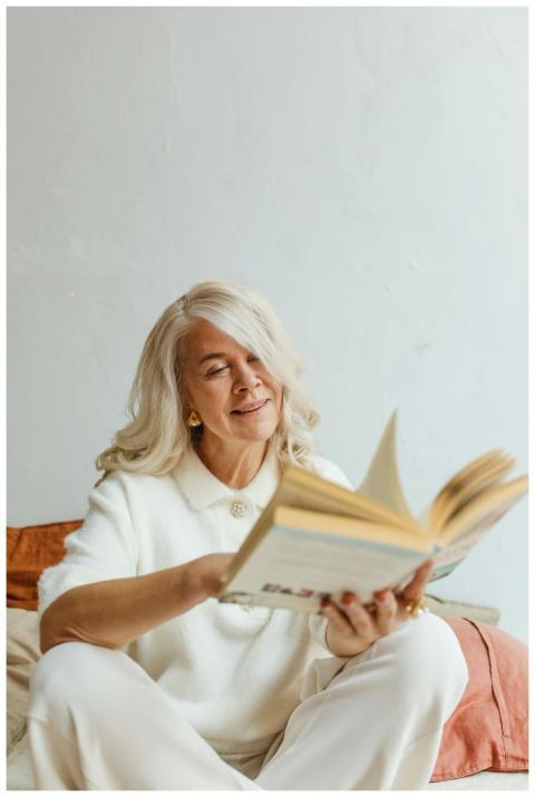 Senior woman with white hair enjoying a book in a