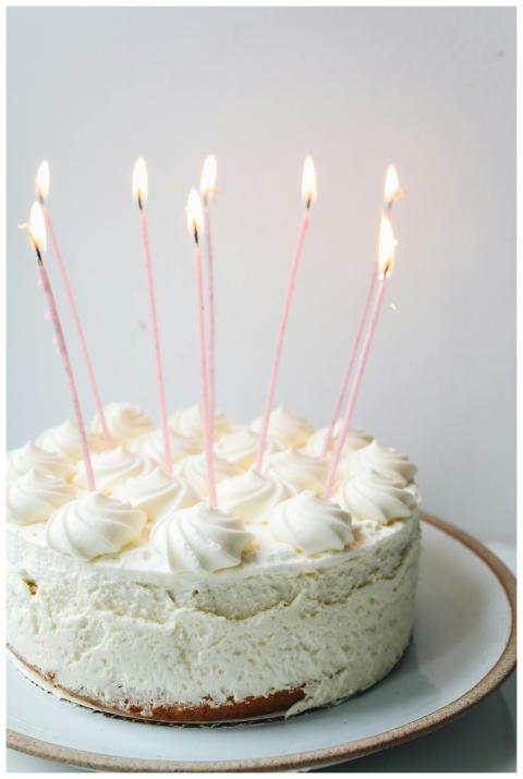 A white frosted birthday cake with lit candles on
