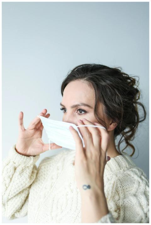 Close-up of a woman putting on a face mask indoors