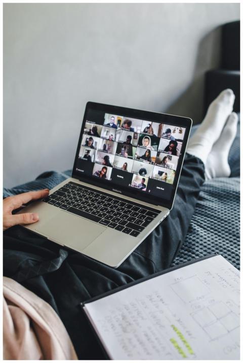 Adult sitting on bed using laptop for video confer
