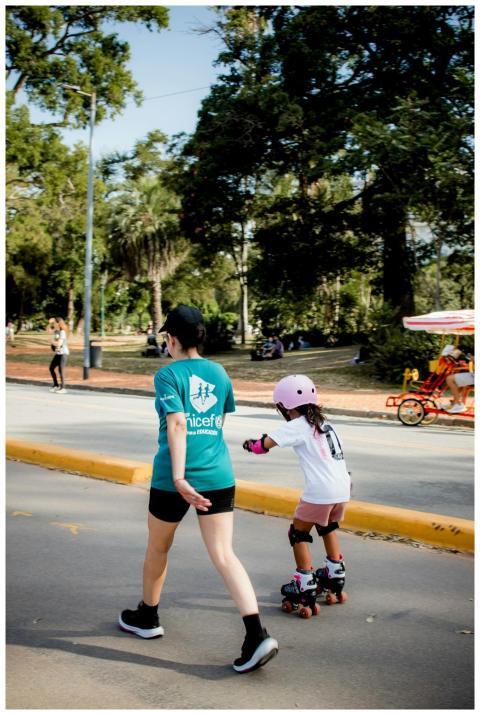 A child in skating gear and an adult walk in the p
