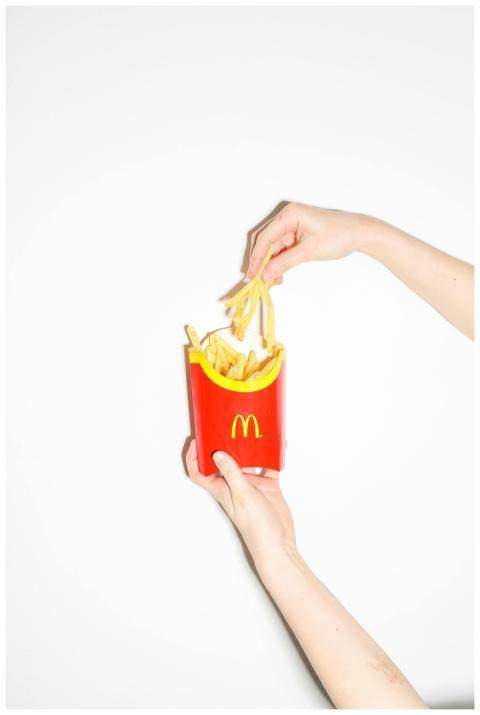 Hands holding classic McDonald's fries on a white
