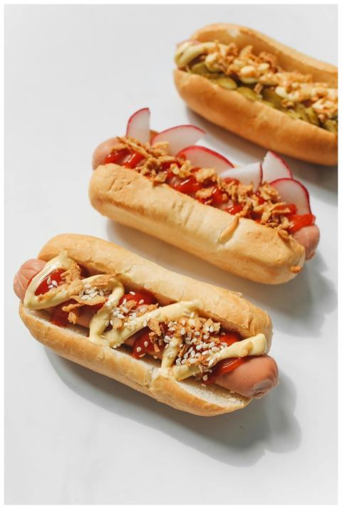 Three gourmet hot dogs topped with mustard, ketchu