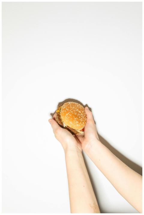 Delicious burger held by hands against a clean whi
