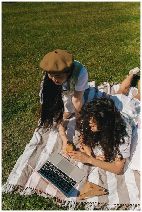 Two women enjoying leisure time on a blanket outdo