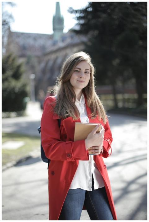 Young woman in a red coat smiling while holding a