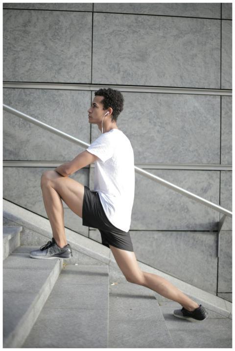 Side view of a young man stretching on a city stai