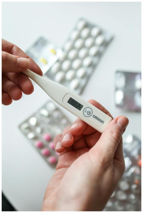 Close-up of hands holding a digital thermometer wi