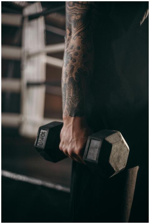 Close-up of a tattooed arm holding a dumbbell in a