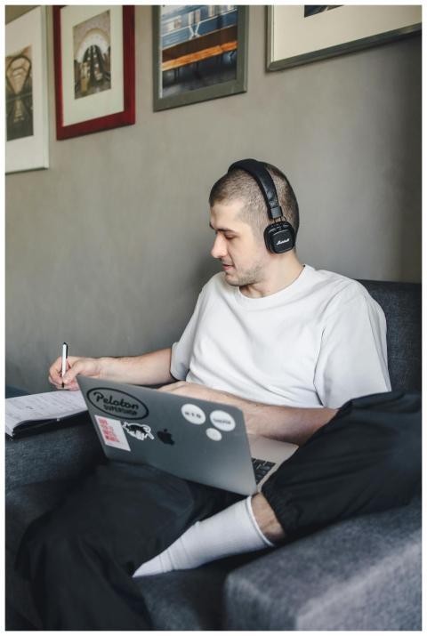 Adult man sitting on a couch, writing in a noteboo