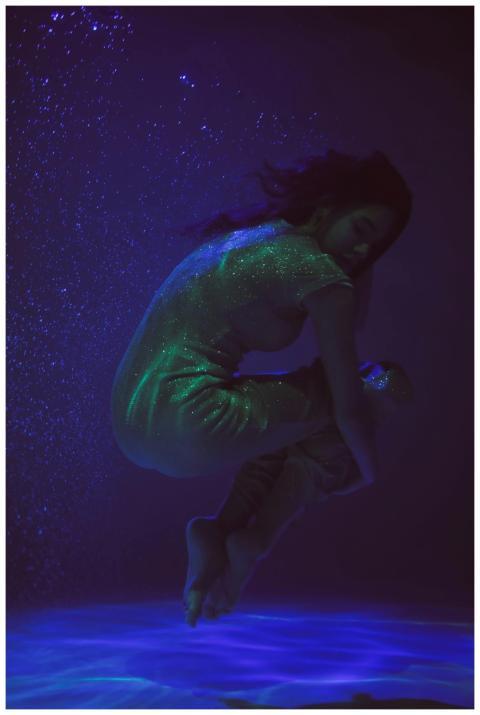 A woman floats gracefully underwater, surrounded b