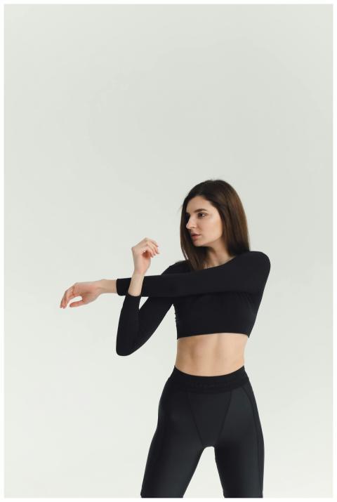 Brunette woman in black activewear stretching in s