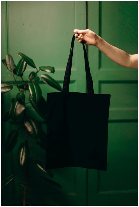 Minimalist black tote bag held by a hand against a