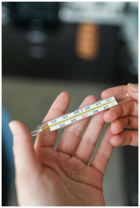 Close-up of hands holding a glass thermometer show