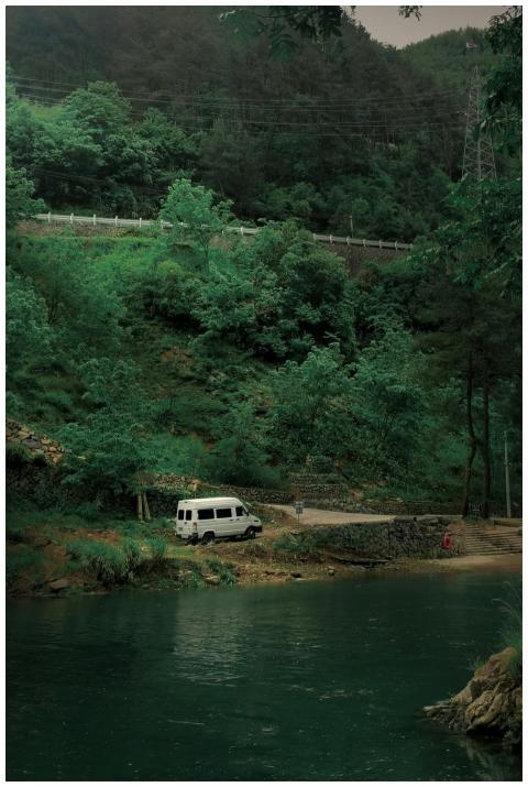 Serene landscape with a white van parked by a rive