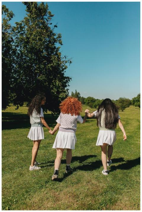 Three students in school uniforms holding hands, w
