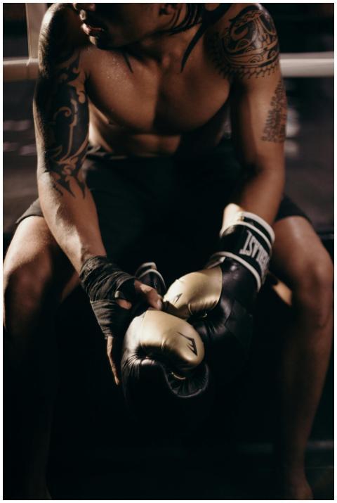 A muscular boxer with tattoos sitting shirtless in