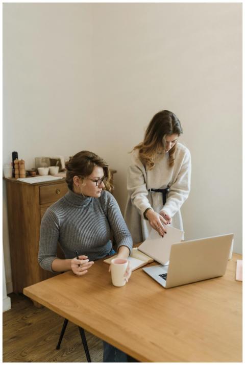 Two women working together at a desk with a laptop