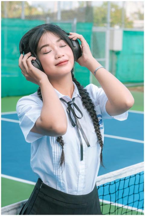 Teenage girl in a uniform enjoying music with head
