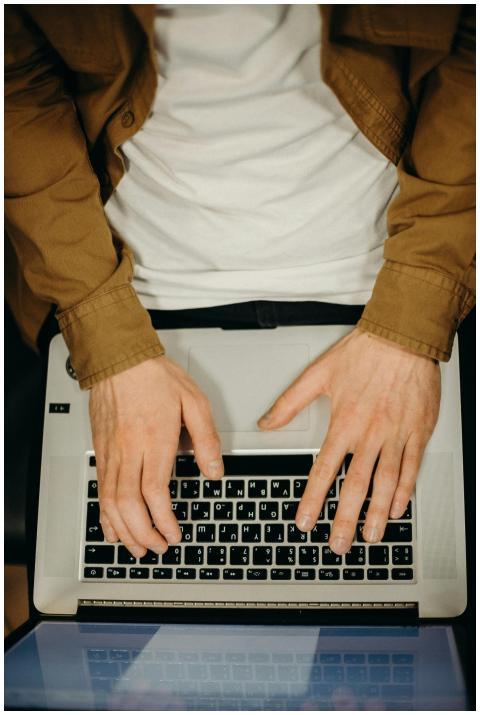 Top view of hands typing on a laptop, showcasing t