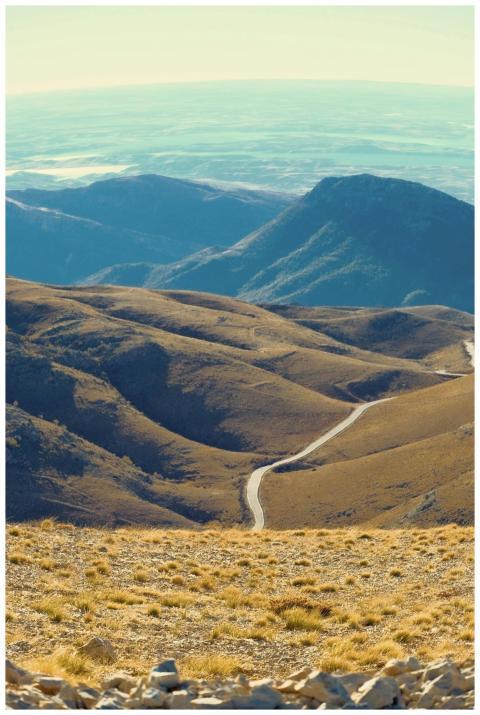 A winding road through a vast, rugged mountain ran