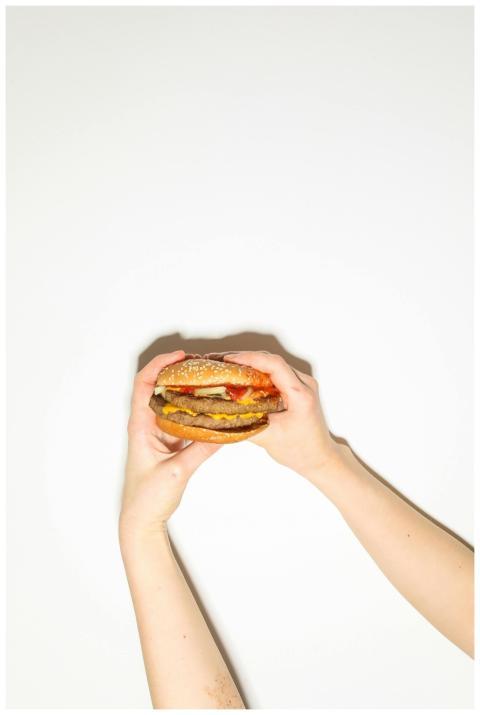 A delicious cheeseburger held by hands on a white