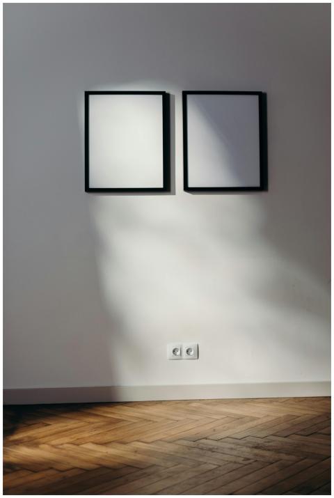 Two black frames casting shadows on a white wall i
