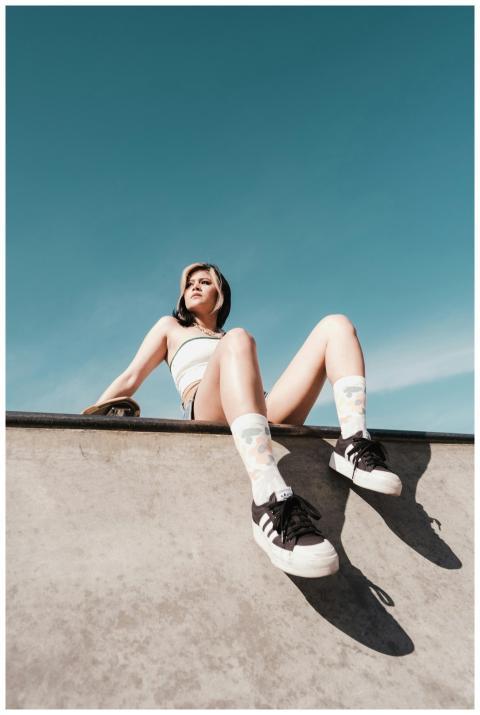 A young woman sitting on a skate park edge, enjoyi