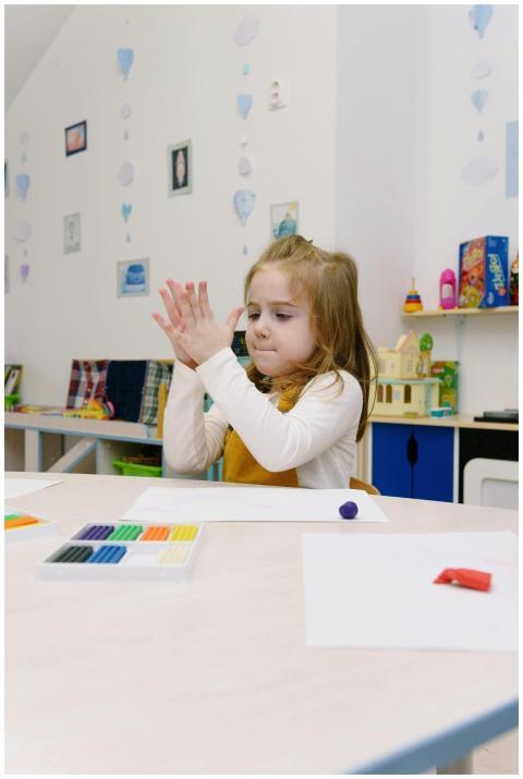 A young girl creatively modeling clay at a desk in