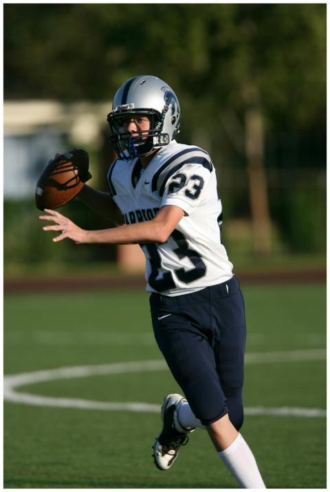 Teen football quarterback in uniform making a pass