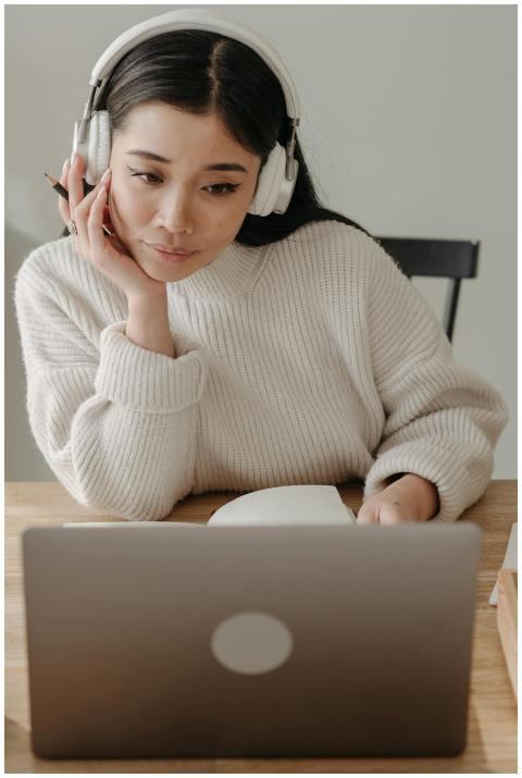 Woman wearing headphones working intently on a lap