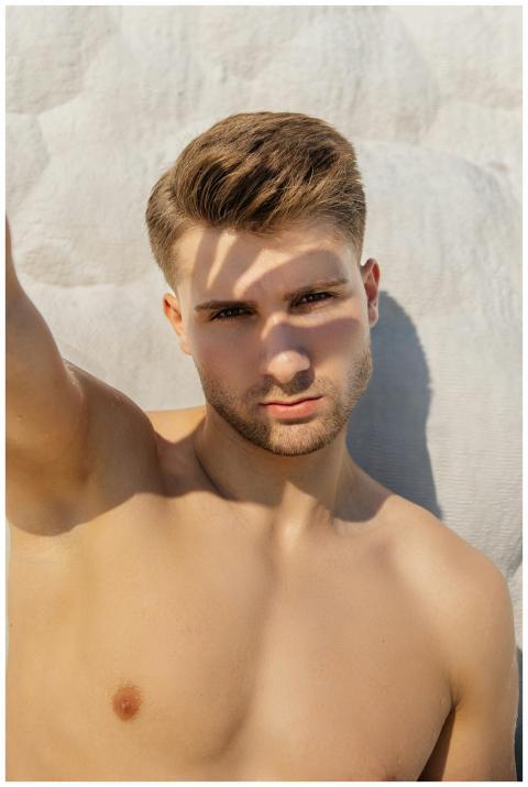 A young man with shadows cast on his face basks in