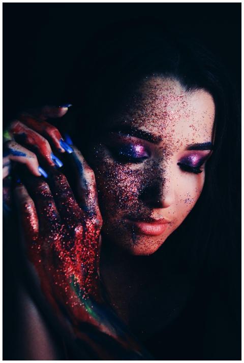 Portrait of a young woman with colorful glitter an