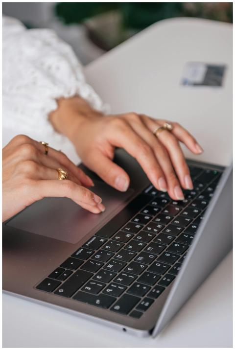 Hands of a woman typing on a laptop keyboard indoo