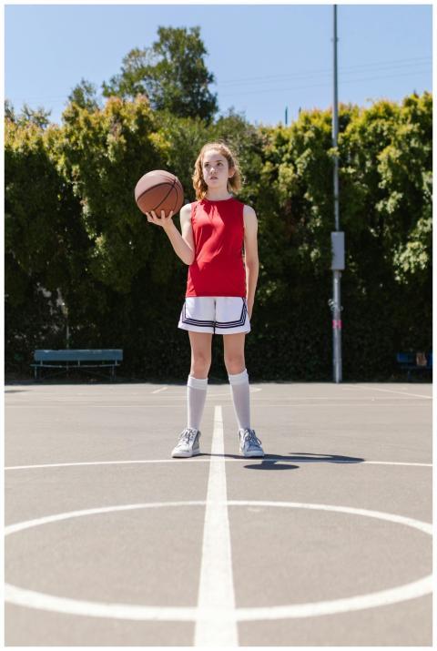Teen girl holding basketball on an outdoor court,