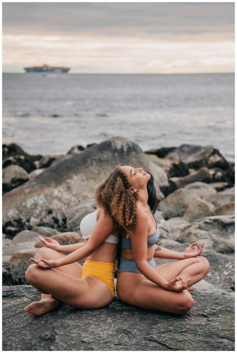 Two women practicing yoga and meditation by the ro