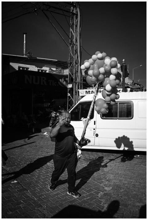 A man carries balloons on a bustling street corner