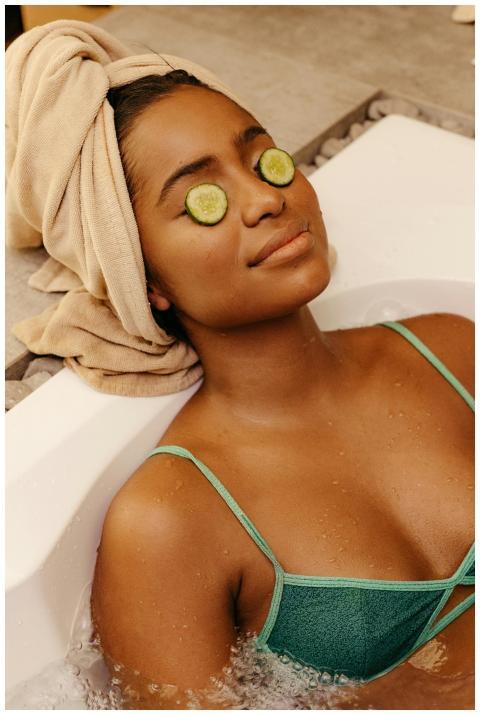 Woman relaxing in a bathtub with cucumber slices o