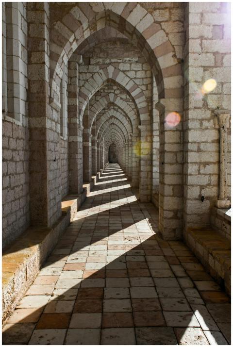 Sunlit stone archway in Assisi, Italy, showcasing