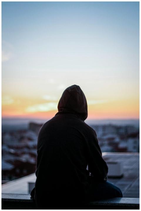 A solitary figure in a hoodie gazes at a vibrant s