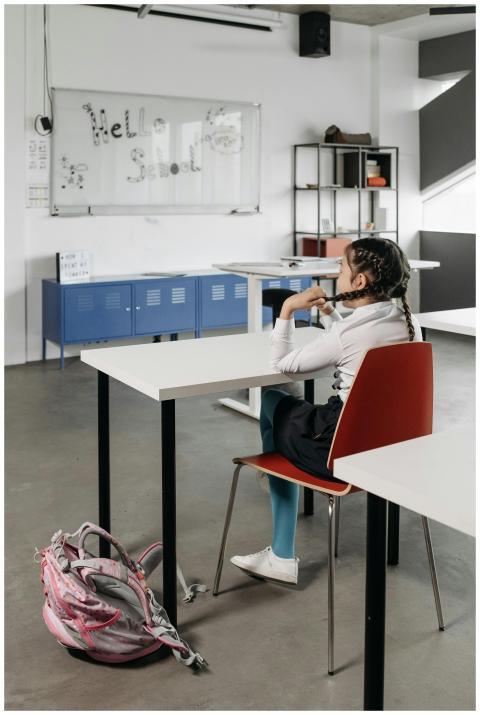 Girl sitting in classroom facing whiteboard with '
