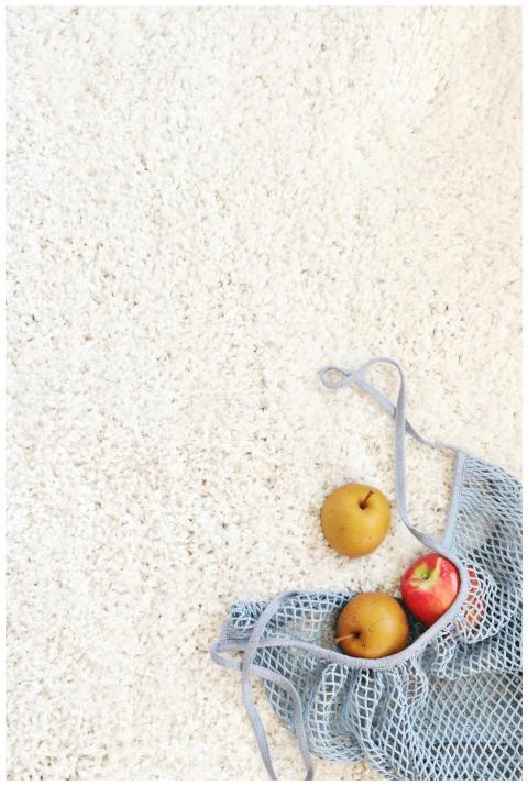 Apples in a blue mesh bag placed on a white carpet