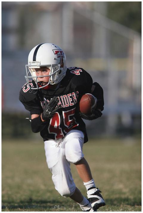 Child athlete playing American football on a sunny